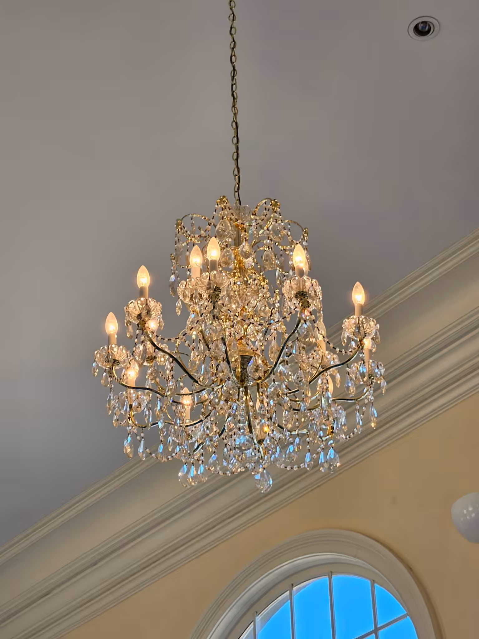 Chandelier dusting specialist carefully removing dust and debris from decorative ceiling light fixture